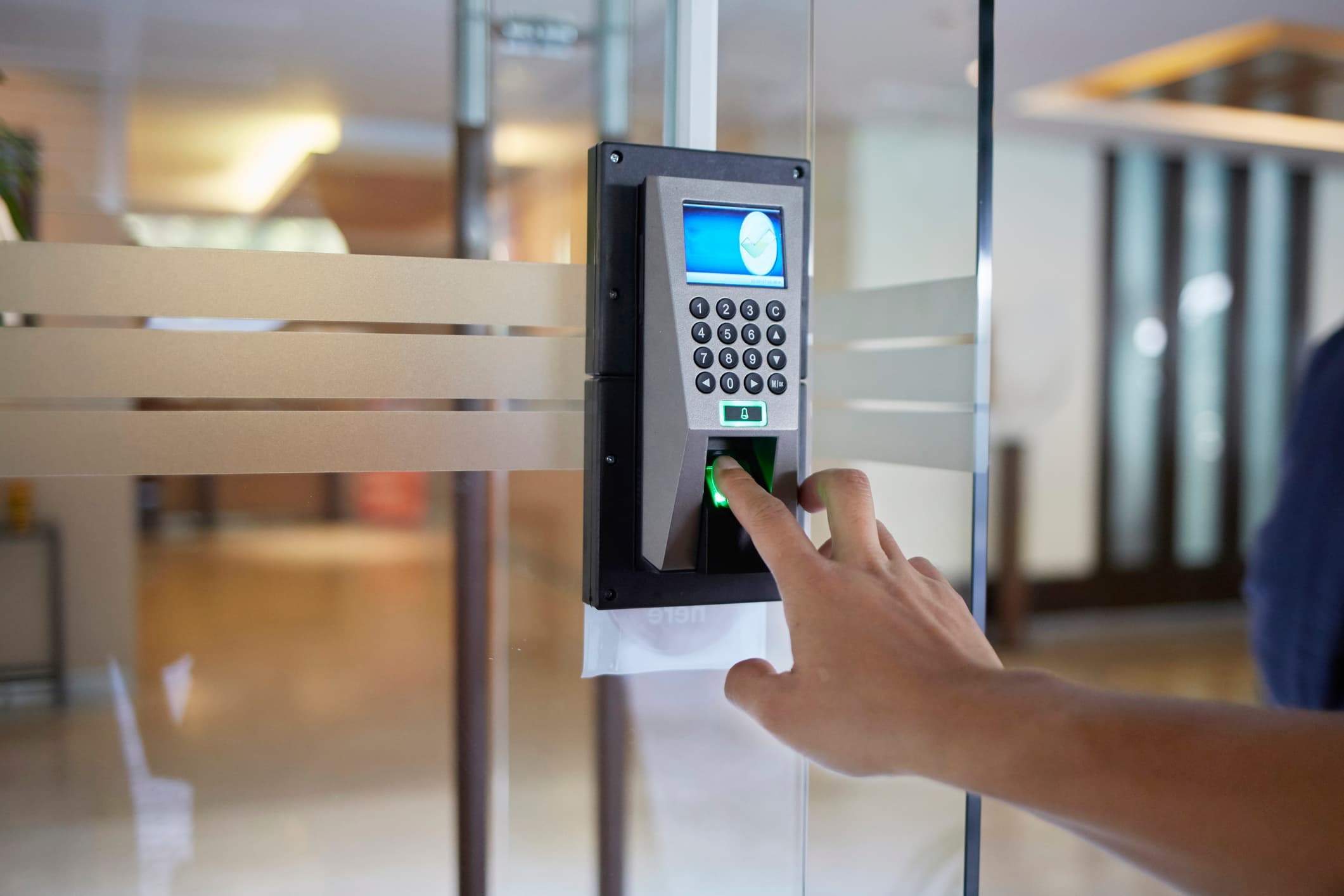 Employee using a fingerprint access control reader at an office door